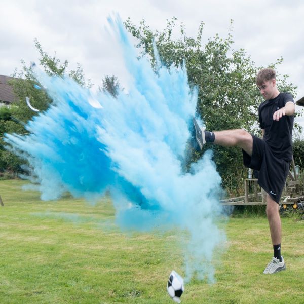 young man kicked a football which exploded releasing blue powder