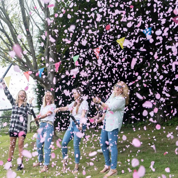 Group of ladies outside releasing pink confetti cannons