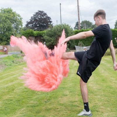 Young male kicking a pink plume of smoke