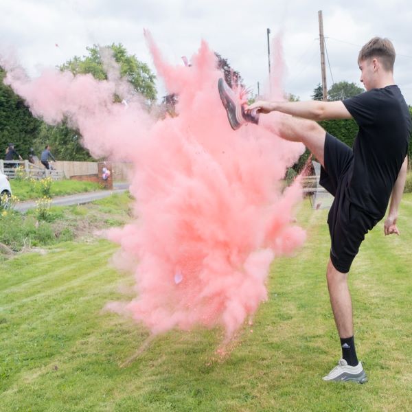 Young Man high kicking through a plume of pink smoke